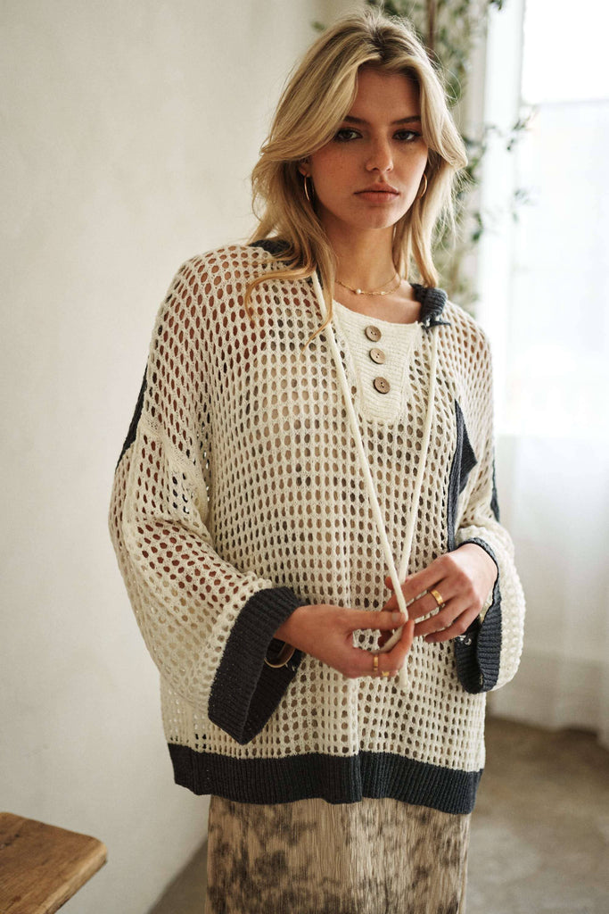 Woman wearing a beige and black patterned cardigan indoors.