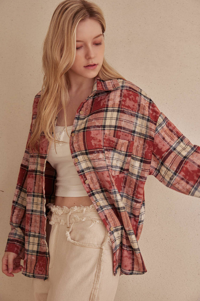 Woman wearing a plaid shirt over a white top and beige pants on a beige background