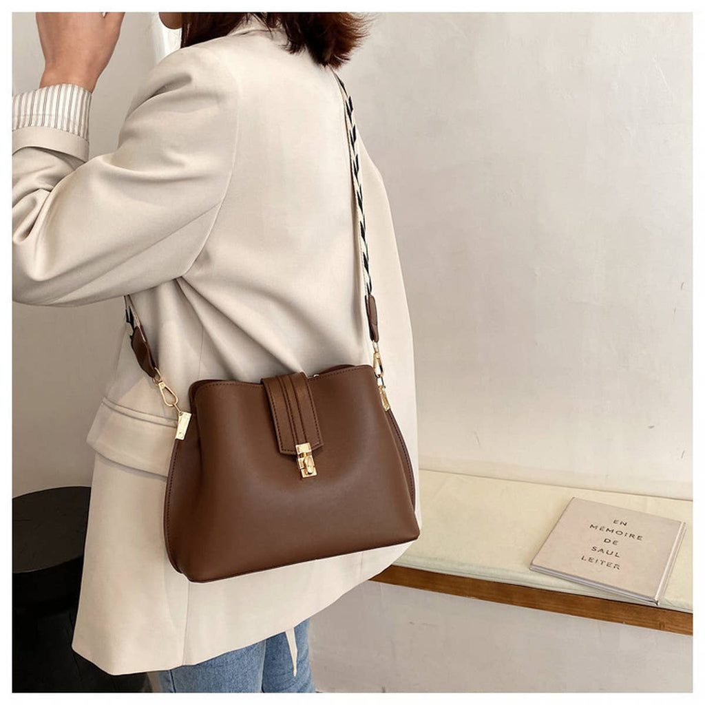 Person wearing a brown handbag with a neutral background