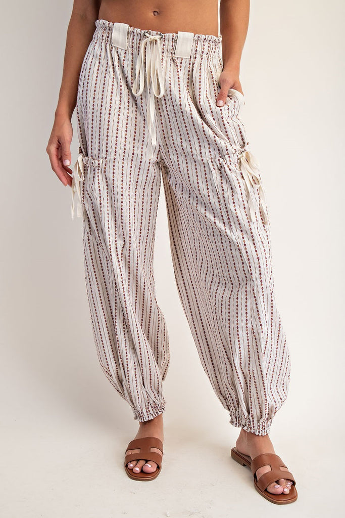 Oatmeal jogger pants with a micro diamond stripe pattern, elastic waistband with contrast drawstring, oversized belt loops, side and back pockets, cargo pockets with cinch ties, and elasticized cuffs