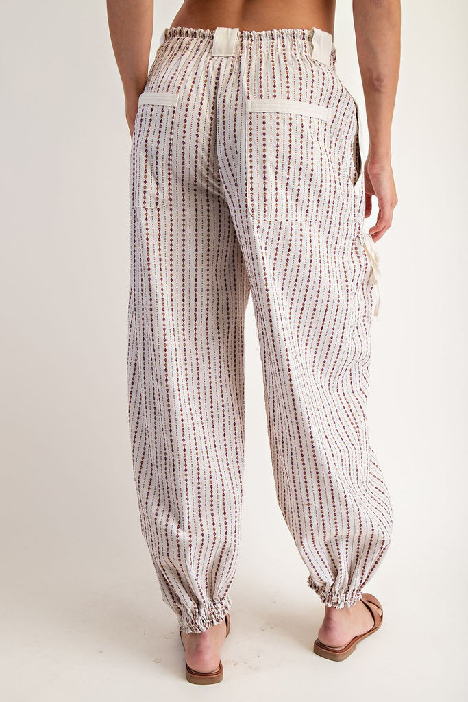 Oatmeal jogger pants with a micro diamond stripe pattern, elastic waistband with contrast drawstring, oversized belt loops, side and back pockets, cargo pockets with cinch ties, and elasticized cuffs