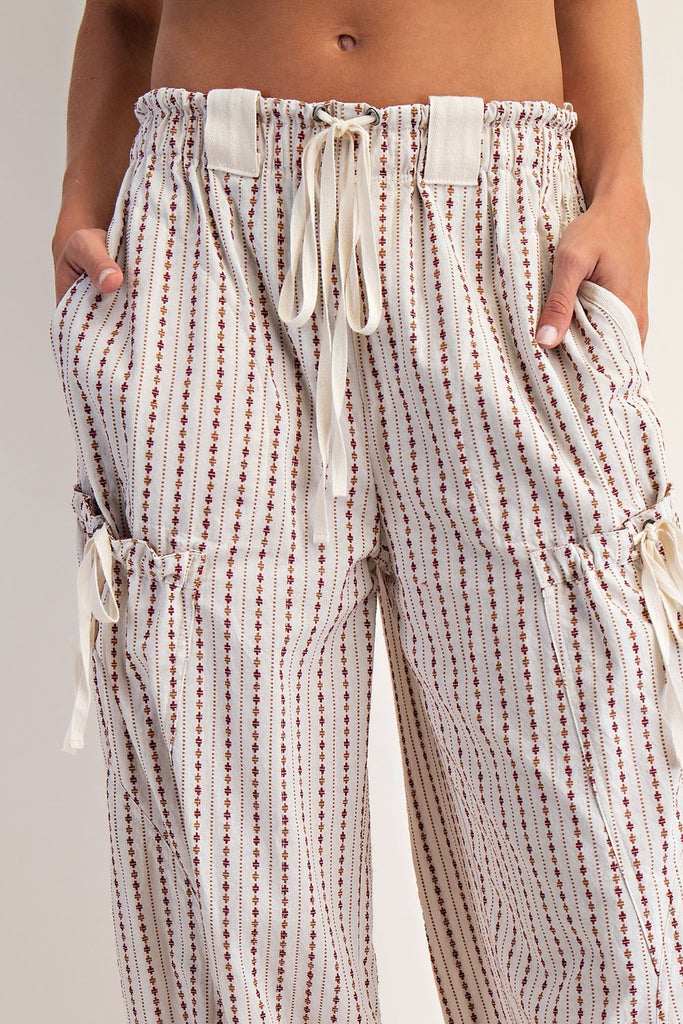 Oatmeal jogger pants with a micro diamond stripe pattern, elastic waistband with contrast drawstring, oversized belt loops, side and back pockets, cargo pockets with cinch ties, and elasticized cuffs