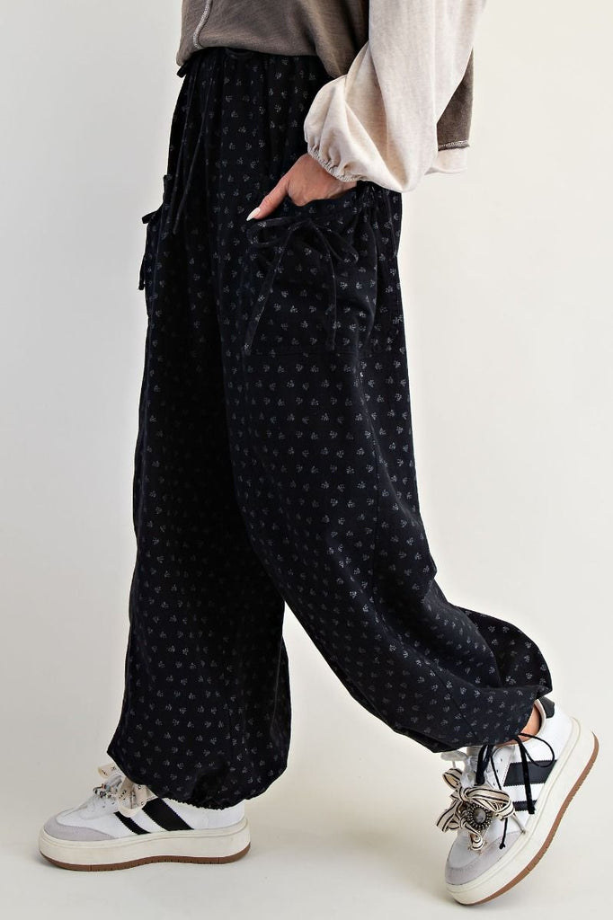 Black mineral-washed wide-leg pants with tonal floral print, elastic drawstring waist, front patch pockets, and adjustable drawstring hems