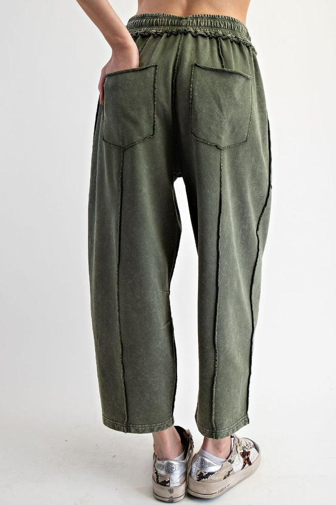 A pair of mineral-washed pine green terry knit barrel pants. The pants have an elastic drawstring waist, large front patch pockets, and exposed seams.