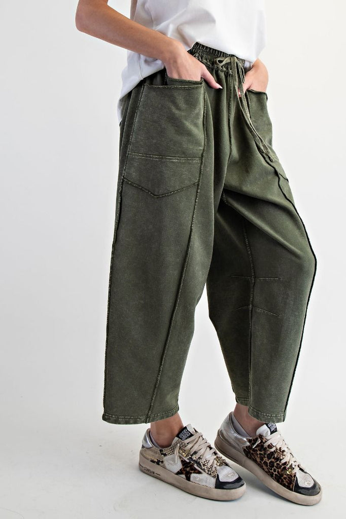 A pair of mineral-washed pine green terry knit barrel pants. The pants have an elastic drawstring waist, large front patch pockets, and exposed seams.