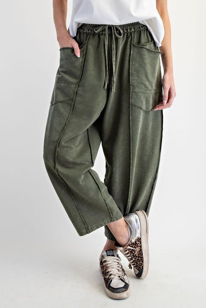 A pair of mineral-washed pine green terry knit barrel pants. The pants have an elastic drawstring waist, large front patch pockets, and exposed seams.