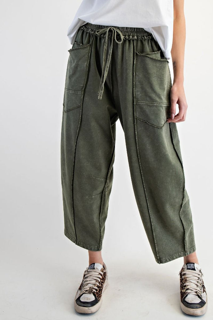 A pair of mineral-washed pine green terry knit barrel pants. The pants have an elastic drawstring waist, large front patch pockets, and exposed seams.