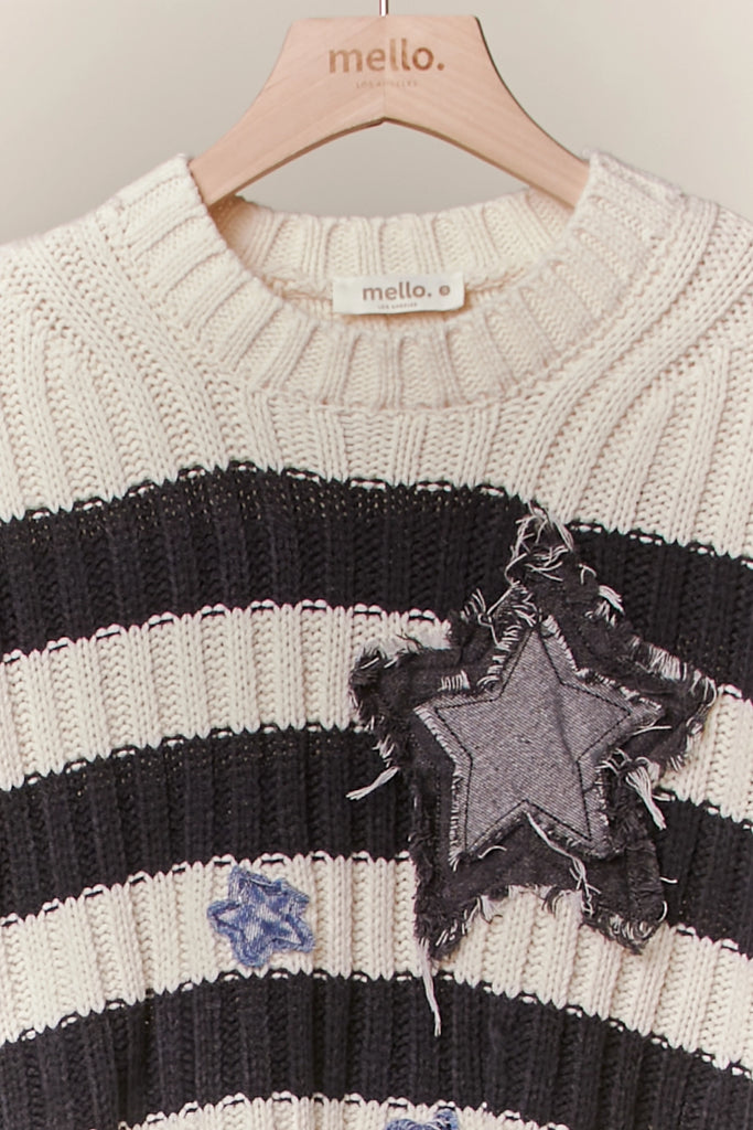 Black and cream striped distressed sweater with star patch and frayed hemline, cropped fit.