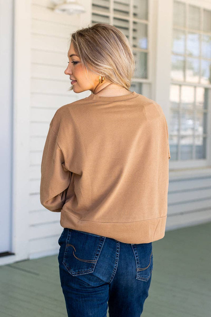 Model wearing the Brynn Camel Classic Pullover — a neutral cropped sweatshirt with crew neck and long sleeves.