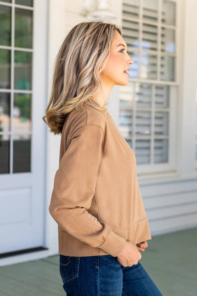 Model wearing the Brynn Camel Classic Pullover — a neutral cropped sweatshirt with crew neck and long sleeves.