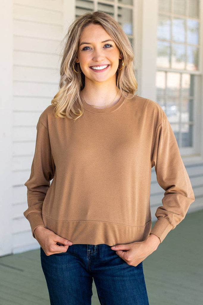 Model wearing the Brynn Camel Classic Pullover — a neutral cropped sweatshirt with crew neck and long sleeves.