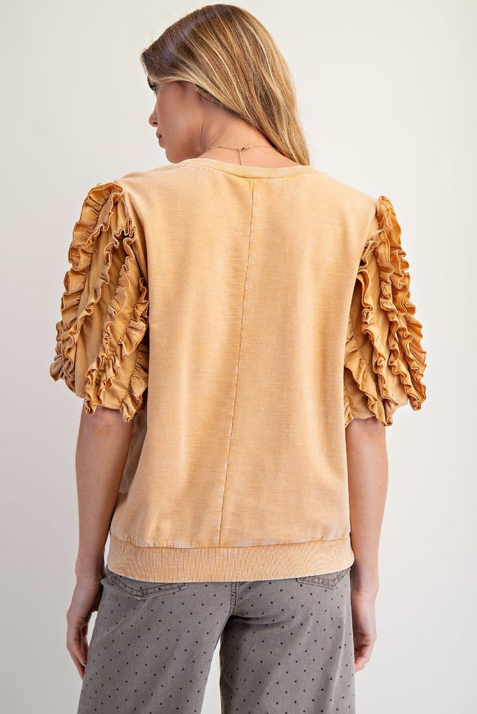 A honey latte-colored, mineral-washed short-sleeve top. It has a crew neck and dramatic, multi-layered ruffled sleeves.