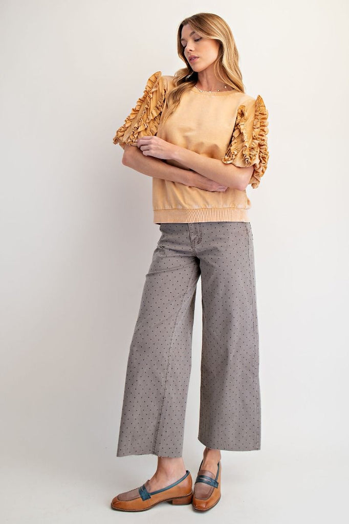 A honey latte-colored, mineral-washed short-sleeve top. It has a crew neck and dramatic, multi-layered ruffled sleeves.