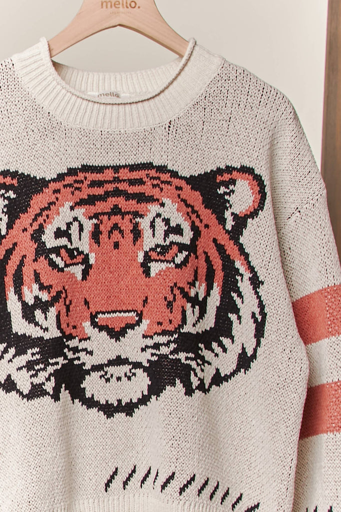  Cream knit sweater with a large tiger face graphic and rust stripe sleeves.