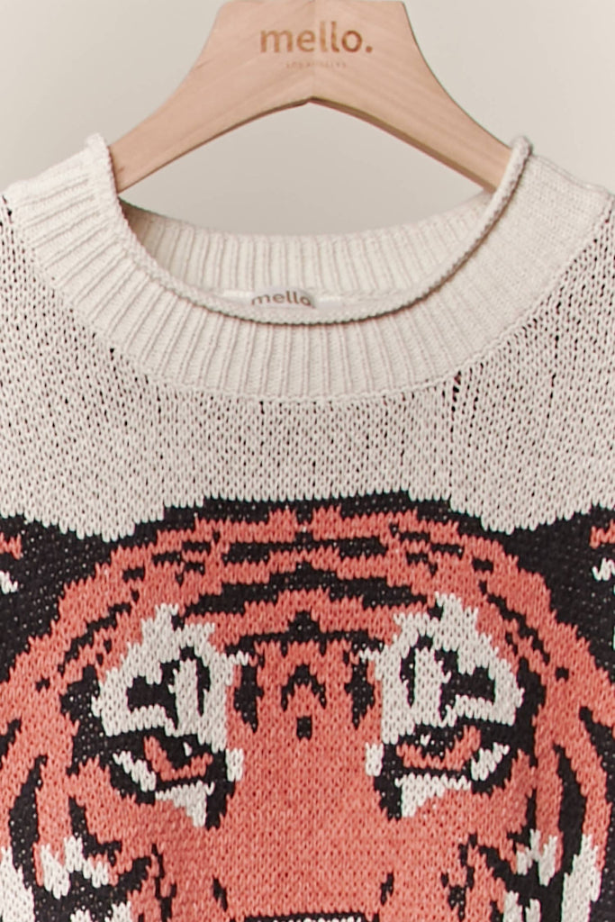 Cream knit sweater with a large tiger face graphic and rust stripe sleeves.
