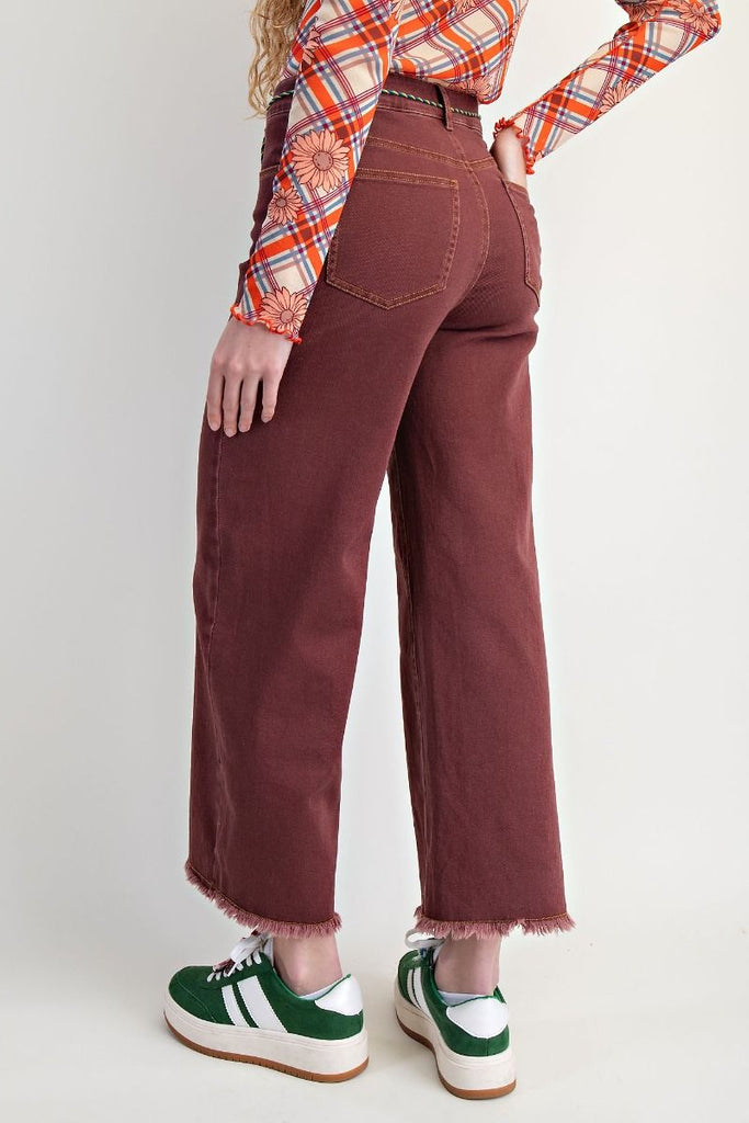 Clementina vintage wine wide-leg jeans with a high-waisted fit and frayed hem, styled with a patterned top and sneakers.