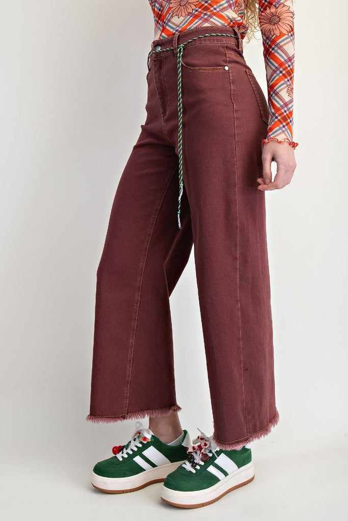 Clementina vintage wine wide-leg jeans with a high-waisted fit and frayed hem, styled with a patterned top and sneakers.