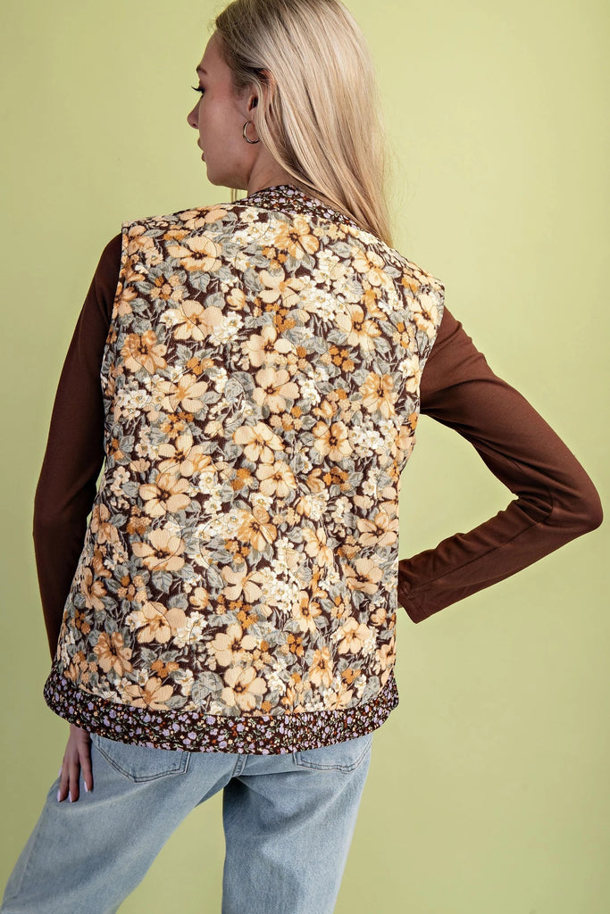 A quilted vest with a brown and cream floral print and two oversized bow ties on the front.