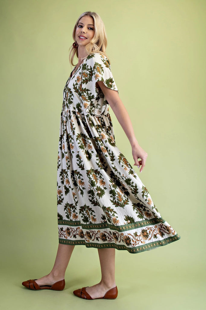 Midi dress with olive and golden floral print, V-neckline, scalloped short sleeves, covered buttons, and flowing skirt with border trim