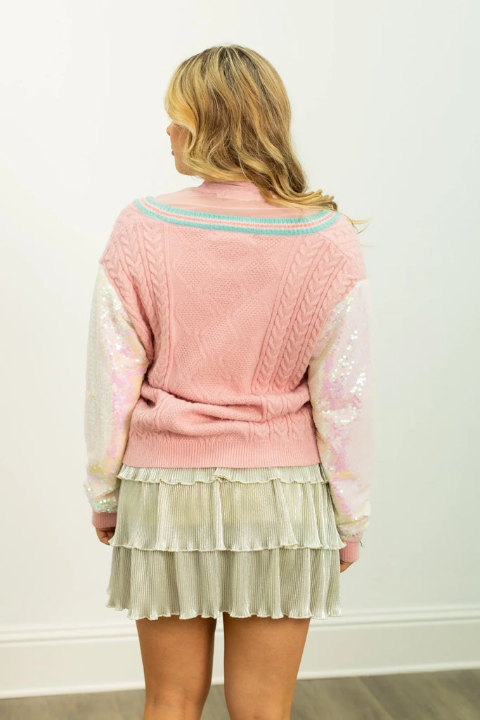 Evalette sequin snowman cardigan in pastel pink with a chunky knit texture, two embroidered snowman appliques, and iridescent sequin sleeves for a festive look.