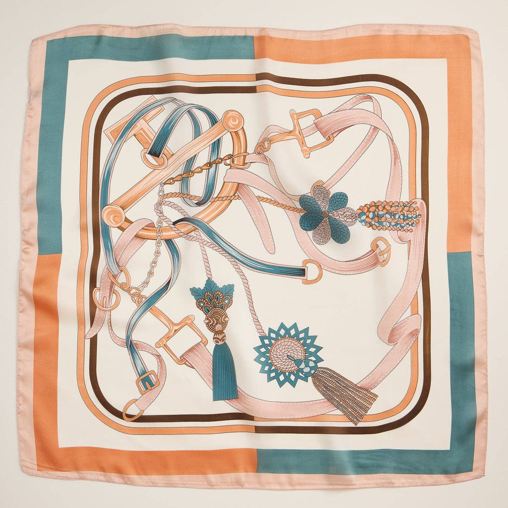 Silk-texture equestrian square scarf with buckles, straps, tassels, and teal-caramel detailing.