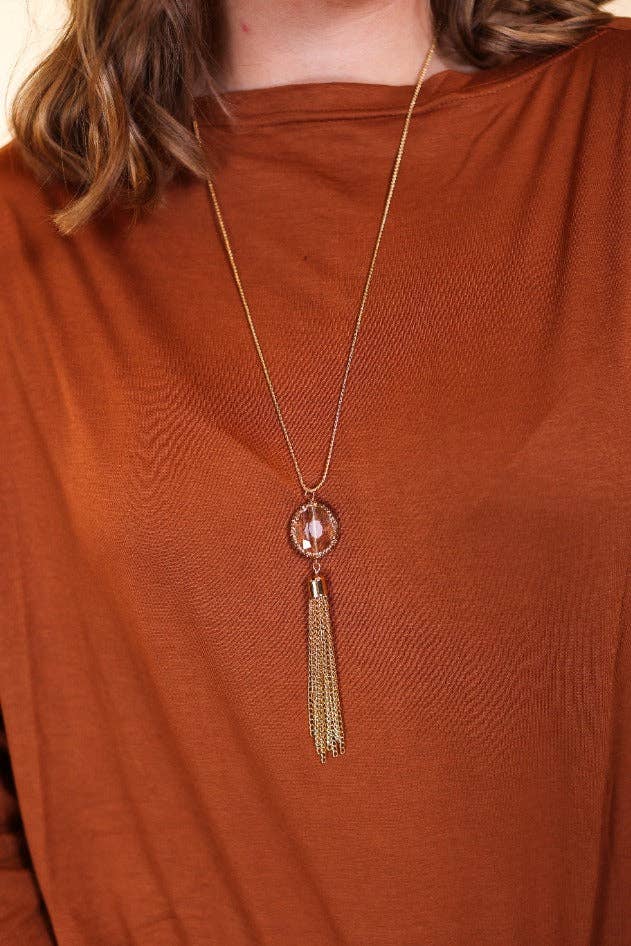 Gold chain necklace featuring a faceted gemstone pendant and cascading gold tassel accent.