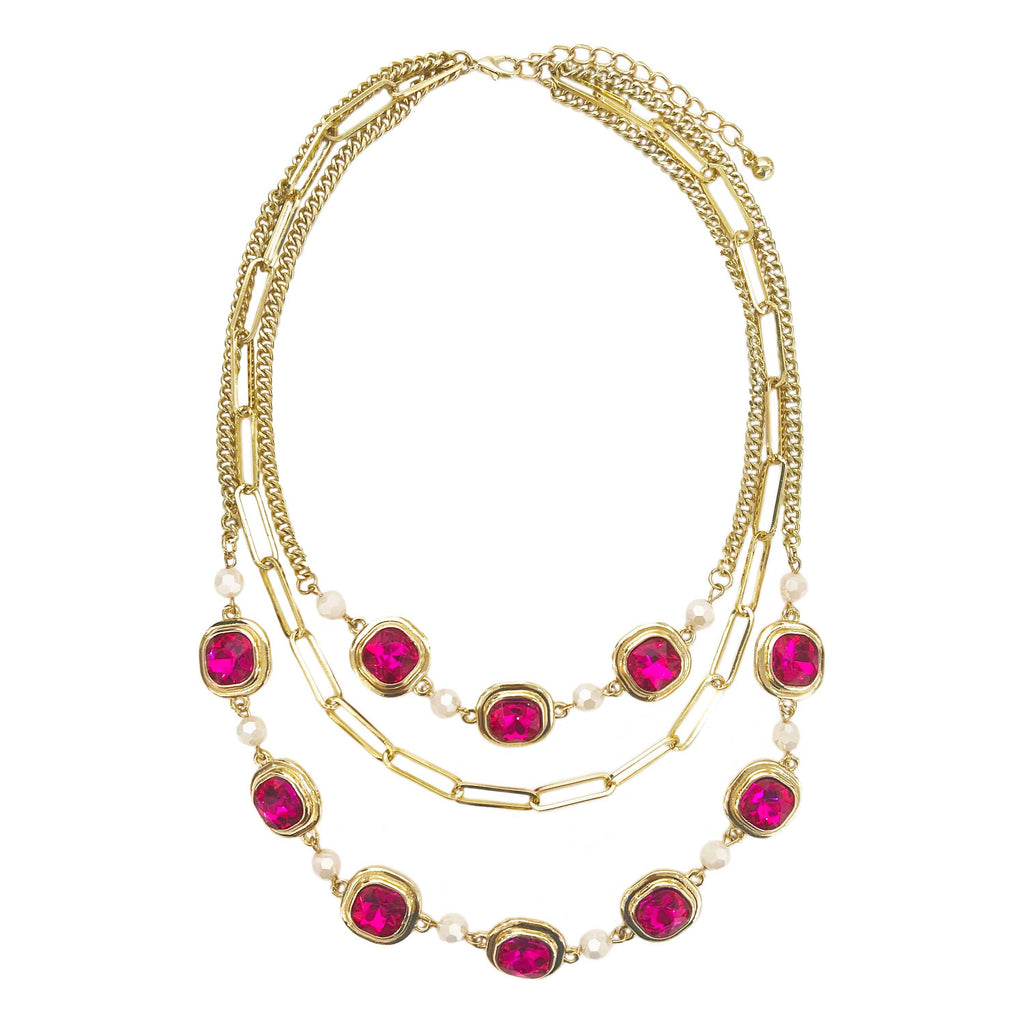 Gold three-strand necklace with vibrant pink stones and pearl accents.