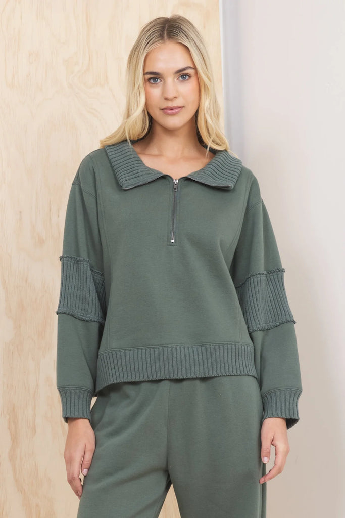 An olive green fleece quarter-zip pullover with a wide, ribbed collar and ribbed panels on the sleeves. The pullover has a relaxed, cropped fit.