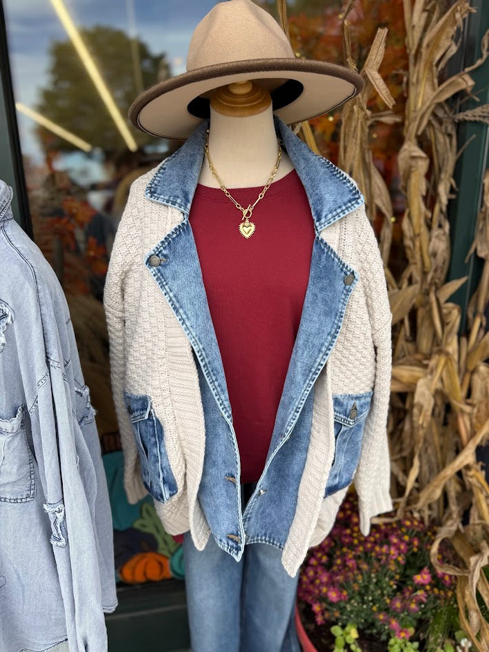 Mannequin wearing a layered outfit with a denim jacket, red top, and beige cardigan in an outdoor setting. “Briar Mixed Media Jacket in cream and denim — relaxed fit collared jacket with button-down front and soft knit and denim panels.”