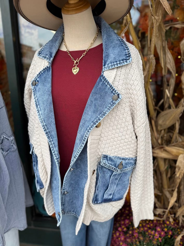 Mannequin wearing a denim and beige jacket with a red shirt underneath, standing against a blurred background.
