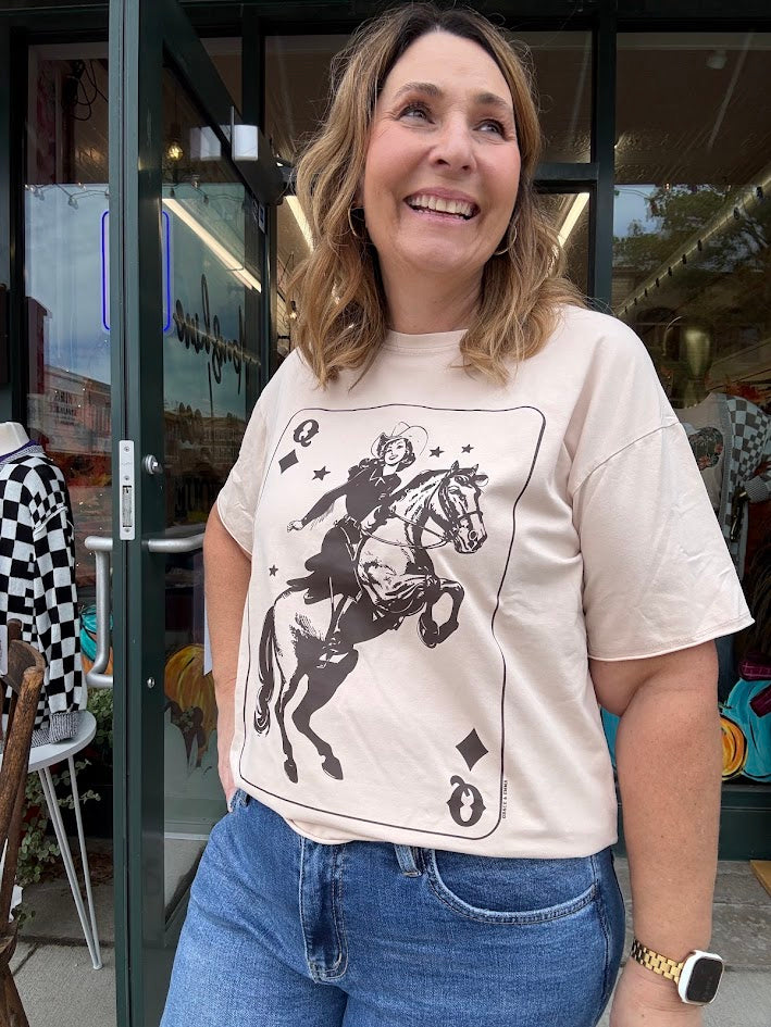 Woman wearing a t-shirt with a graphic design of a person on a horse, standing in front of a store entrance.