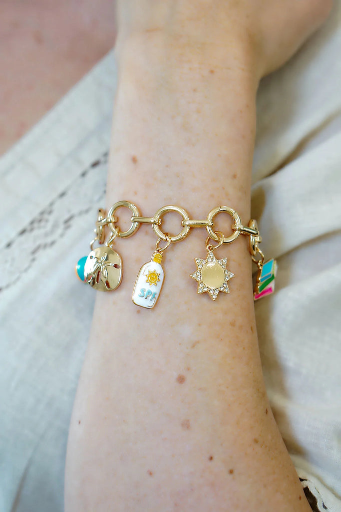Bracelet with various charms on a wrist against a neutral background