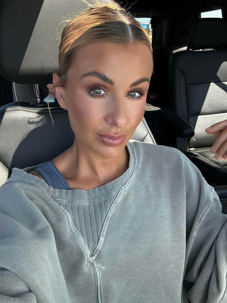 Woman sitting in a car wearing a gray sweatshirt