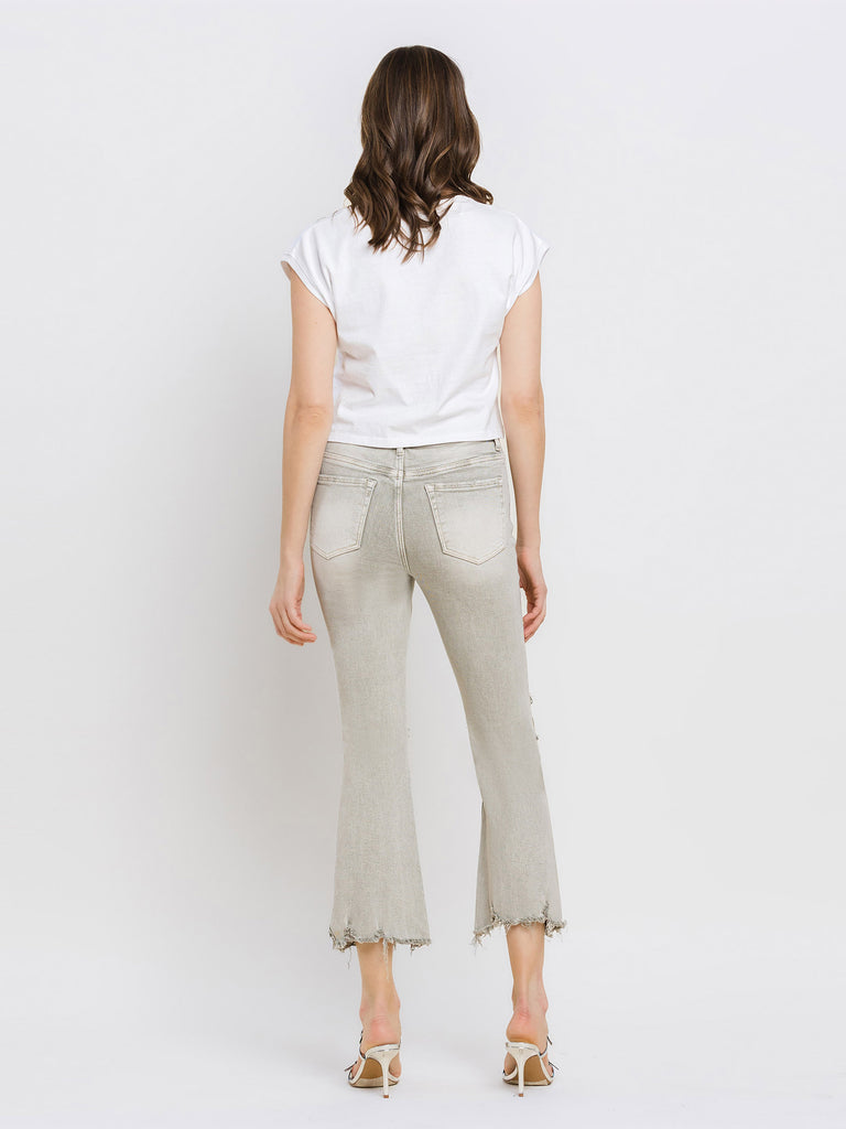 Woman wearing light moss green pants and a white top on a plain background
