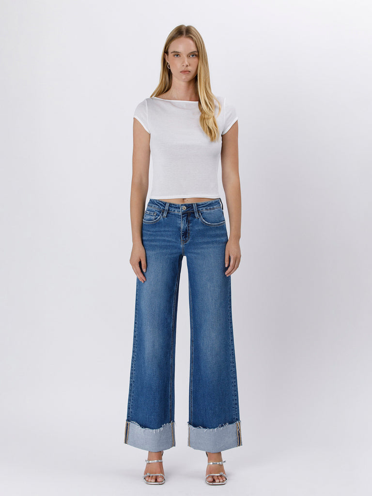 Woman wearing a white top and blue jeans on a white background