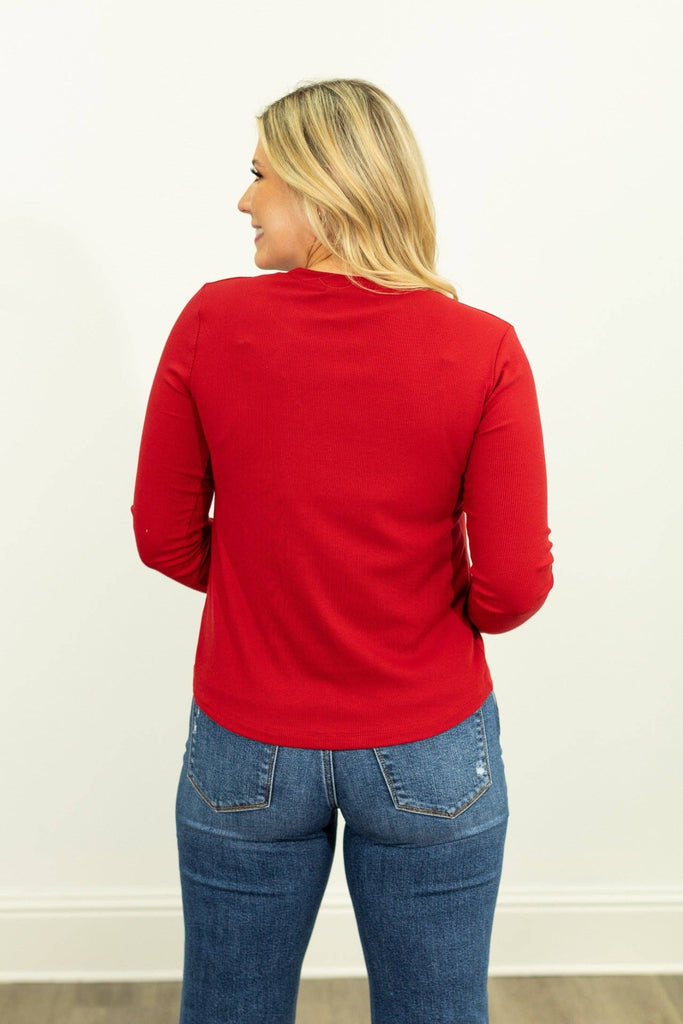 Model wearing the Lennon Red Ribbed Long Sleeve Top — fitted red ribbed shirt with crew neckline and thumbhole sleeves.