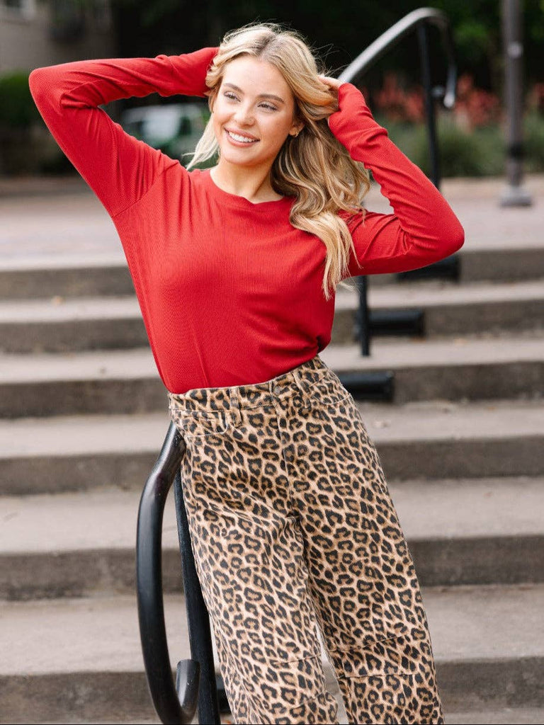 Model wearing the Lennon Red Ribbed Long Sleeve Top — fitted red ribbed shirt with crew neckline and thumbhole sleeves.