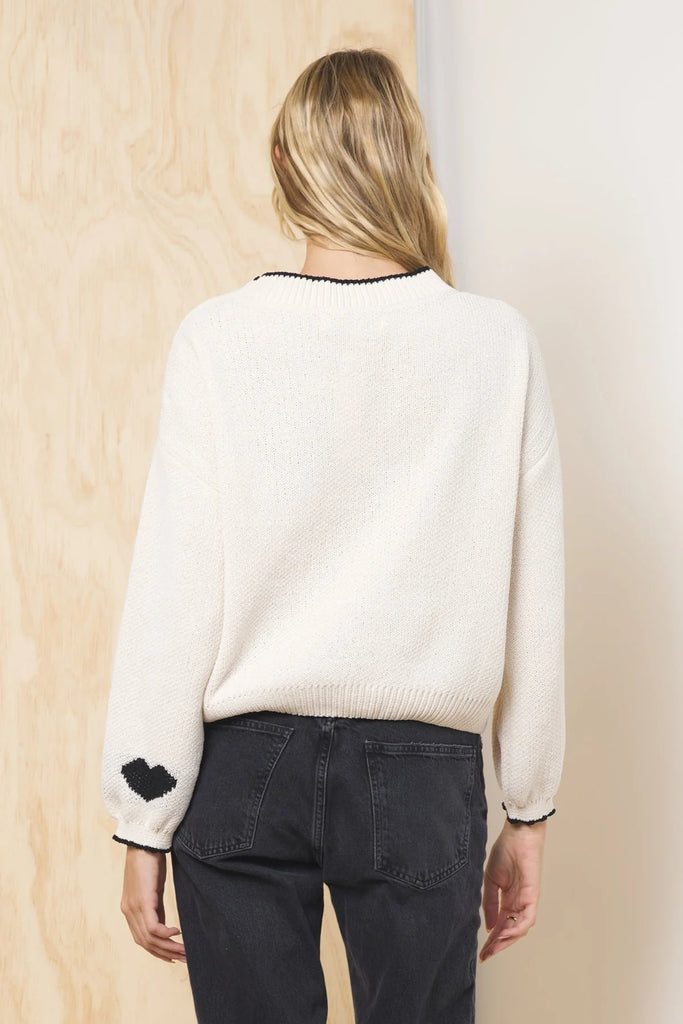 An ivory jacquard knit sweater with the phrase "Take Me To Paris" in black lettering on the front. It has a crew neck with black trim and long, balloon-style sleeves.