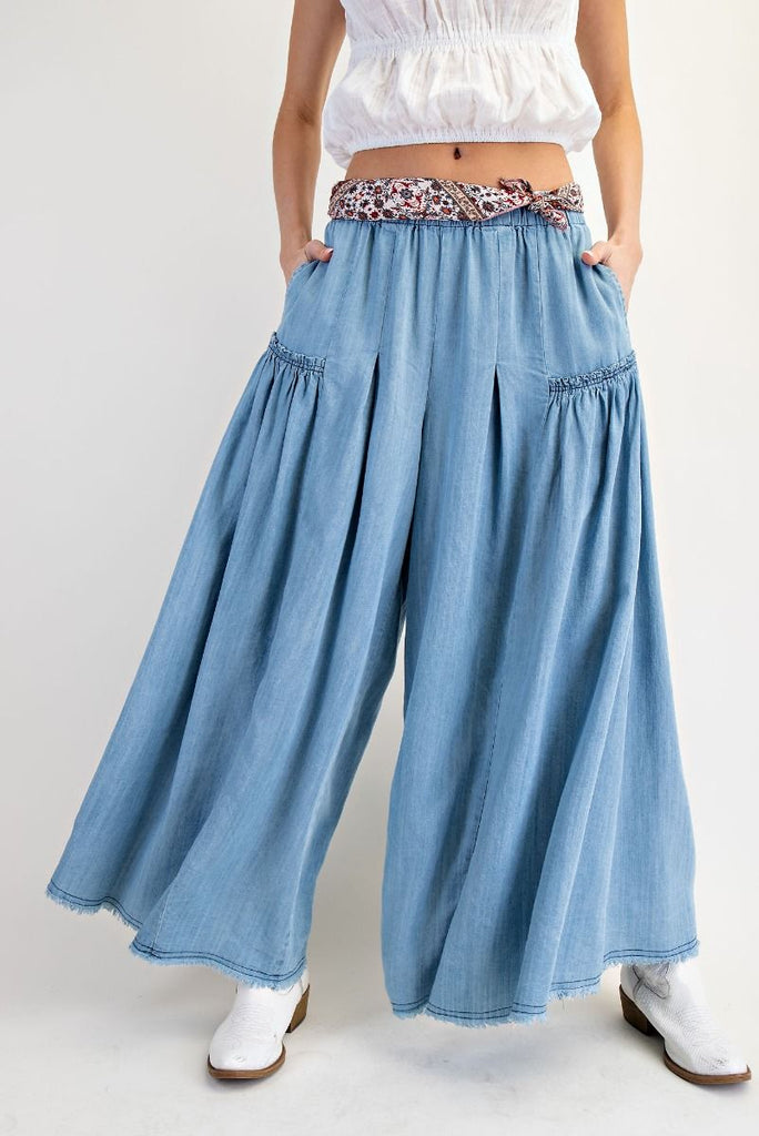 Light wash chambray tiered wide-leg pants with elastic paper-bag waist, patterned fabric tie belt, and flowing silhouette for a bohemian and comfortable style