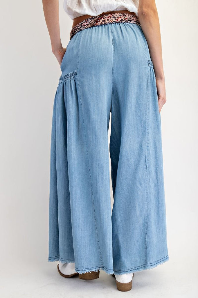 Light wash chambray tiered wide-leg pants with elastic paper-bag waist, patterned fabric tie belt, and flowing silhouette for a bohemian and comfortable style