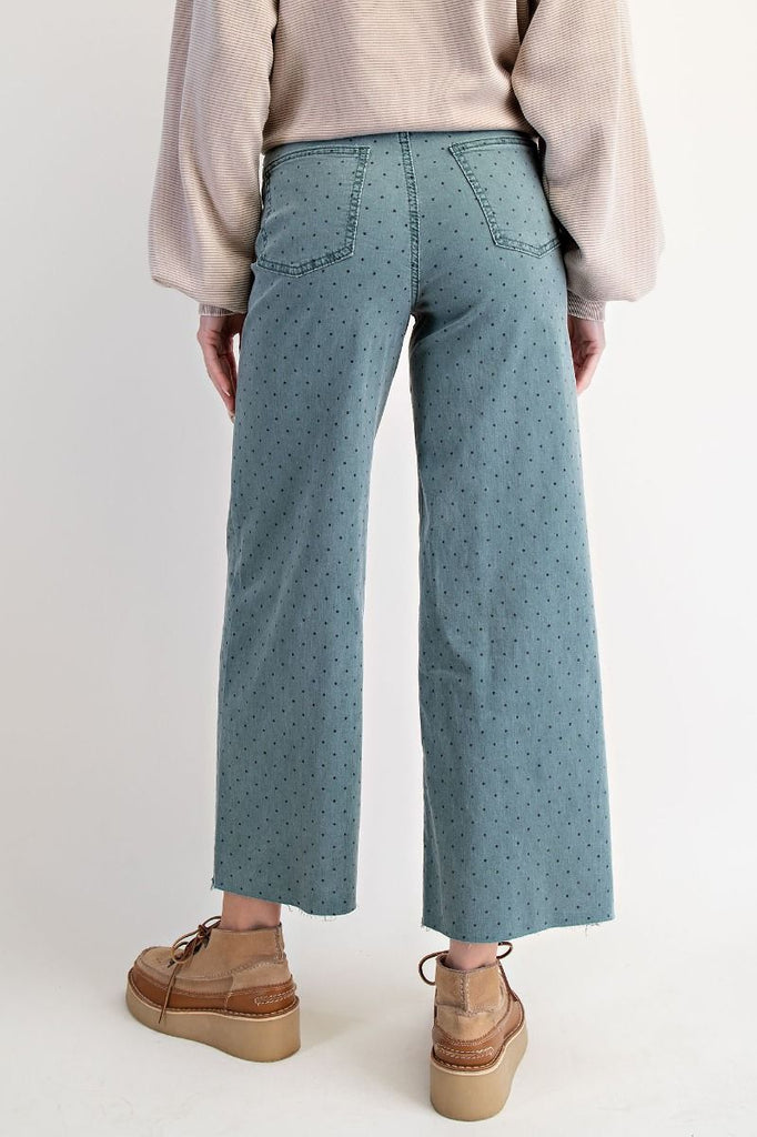 A pair of high-waisted, wide-leg, cropped pants in a teal green washed twill with a black polka dot print.