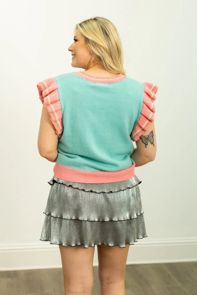 Molly Merry sweater vest in pastel mint green and pink with ruffled sleeves and gold threading, a relaxed V-neck fit, perfect for a cheerful holiday look.