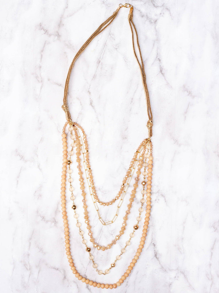 Neutral multi-strand layered necklace with champagne crystal beads, gold accents, and rope sides.