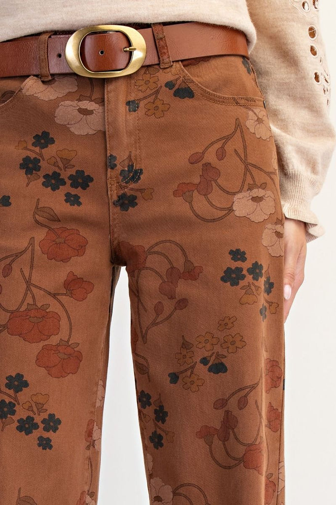 A pair of mocha-colored, high-waisted, wide-leg pants with a warm-toned floral print. The pants are cropped with a frayed hem.