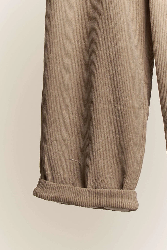 Ottilie Mello corduroy wide-leg crop pants in a neutral beige color, featuring an elastic drawstring waist and a cuffed hem, styled on a hanger.