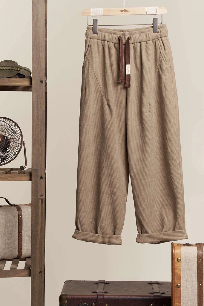 Ottilie Mello corduroy wide-leg crop pants in a neutral beige color, featuring an elastic drawstring waist and a cuffed hem, styled on a hanger.