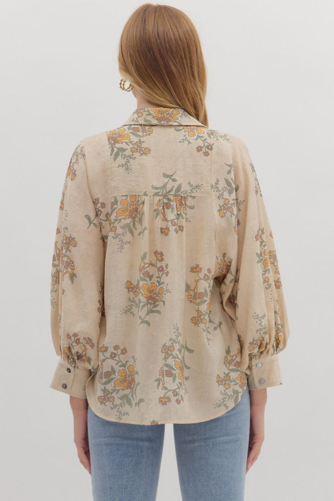An ecru-colored button-down top with a vintage-style floral print in yellow, green, and orange. The top has a classic collar and long, slightly voluminous sleeves with buttoned cuffs.