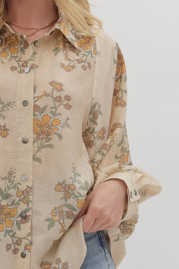 An ecru-colored button-down top with a vintage-style floral print in yellow, green, and orange. The top has a classic collar and long, slightly voluminous sleeves with buttoned cuffs.