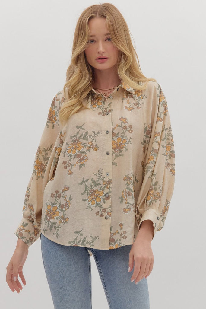 An ecru-colored button-down top with a vintage-style floral print in yellow, green, and orange. The top has a classic collar and long, slightly voluminous sleeves with buttoned cuffs.
