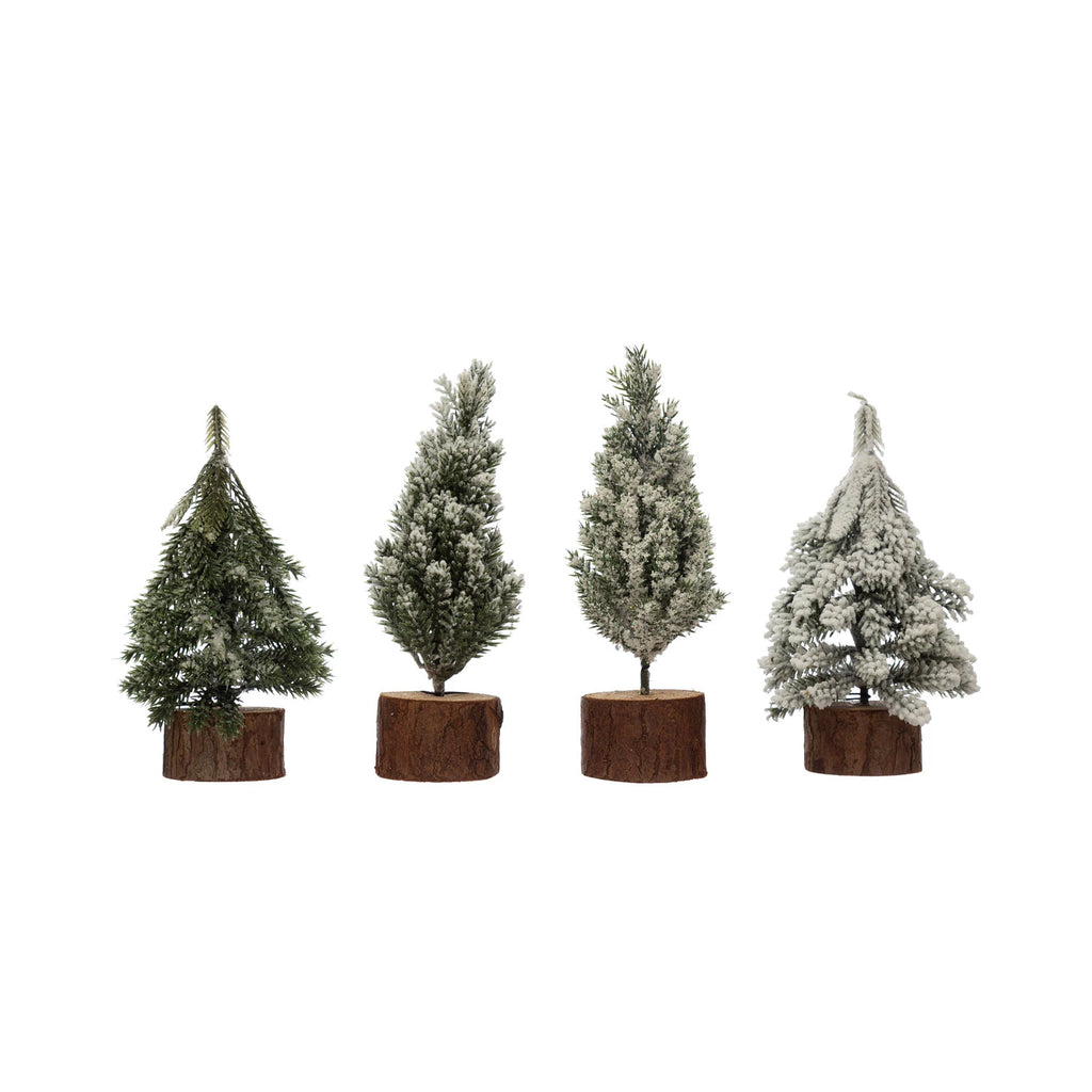 Four styles of faux pine trees with snow finish and natural wood slice bases, 5.75"–6.75" tall, rustic holiday tabletop decorations.